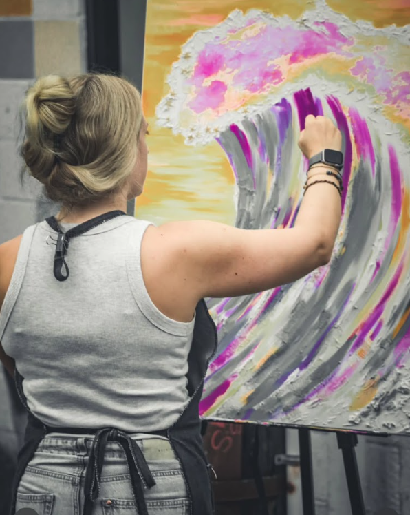 Michaela painting a large colorful wave on canvas